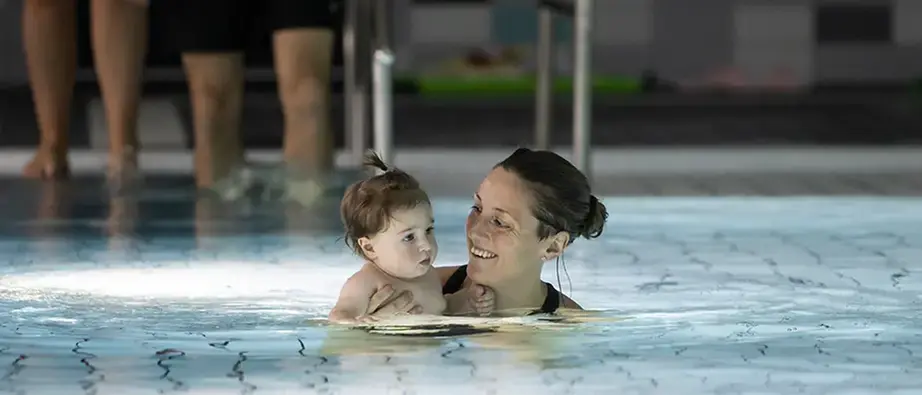 En mamma med sitt barn i bassängen.